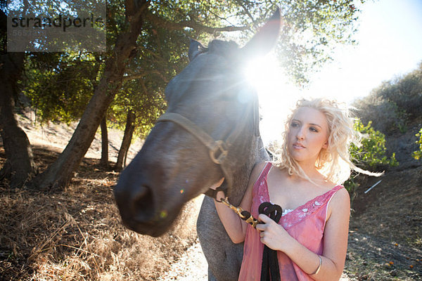 Junge Frau mit Pferd im Sonnenlicht