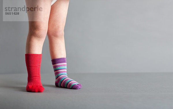 Kind in einer roten Socke und einer gestreiften Socke
