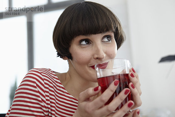 Junge Frau sitzend mit einem Glas Tee in der Wohnung