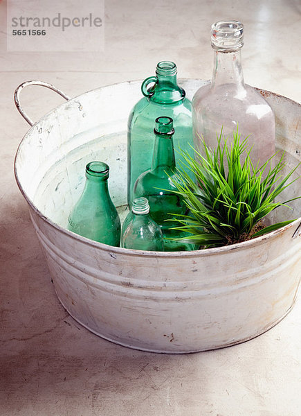 Flaschen und Pflanzen in einem alten Bottich