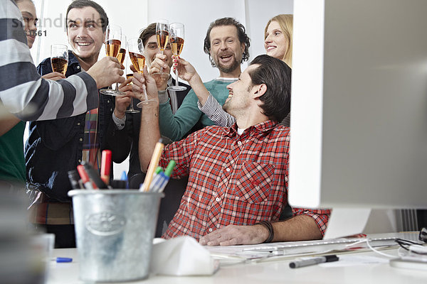 Männer und Frauen toasten mit Champagner im Büro