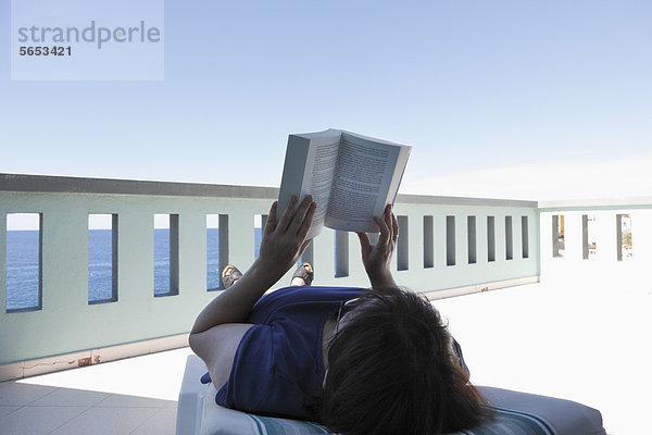 Spanien  Kanarische Inseln  La Palma  Reife Frau liest Buch auf dem Balkon