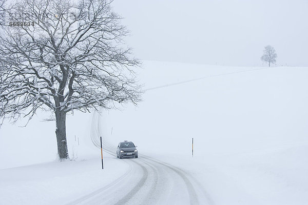 Deutschland  Oberbayern  Blick auf das Auto auf verschneiter Straße