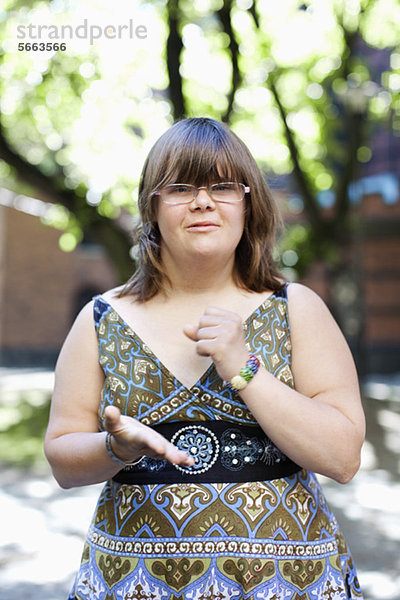 Portrait einer jungen Frau mit Down-Syndrom in Gebärdensprache