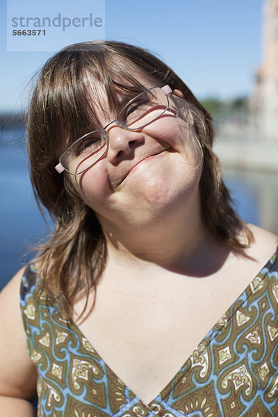 Nahaufnahme Porträt einer süßen Frau mit Down-Syndrom  die im Freien lächelt.
