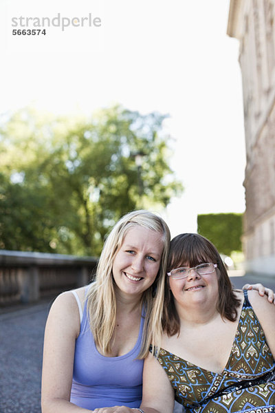 Porträt einer Frau mit Down-Syndrom  die mit einem Freund zusammensitzt.