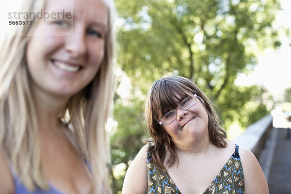 Porträt einer Frau mit Down-Syndrom lächelnd mit ihrer persönlichen Assistentin