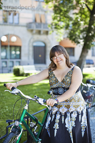 Portrait einer jungen Frau mit Down-Syndrom lächelnd mit Fahrrad