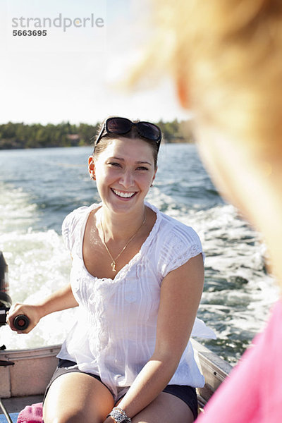 Lächelnde Frau  die ihren Freund auf dem Motorboot ansieht.