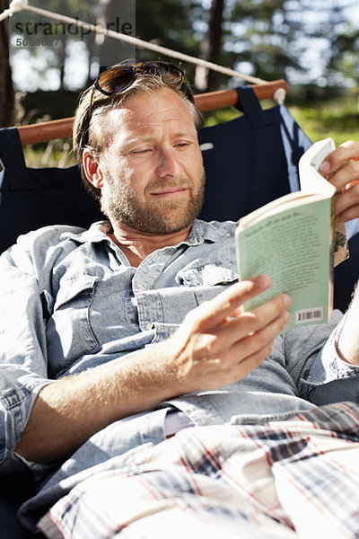 Entspannter Mann liest Buch auf Hängematte