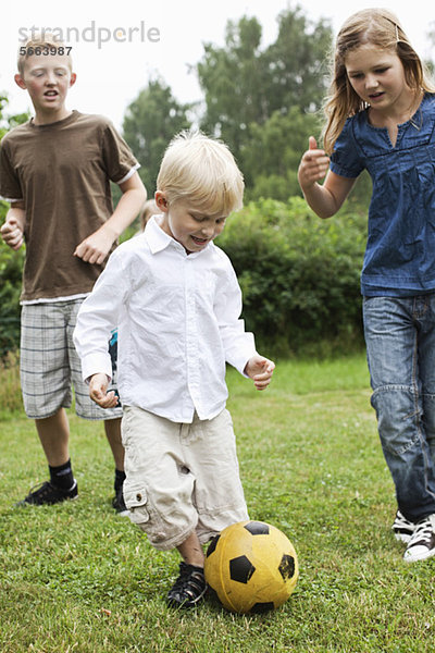 Geschwister spielen Fußball im Hinterhof