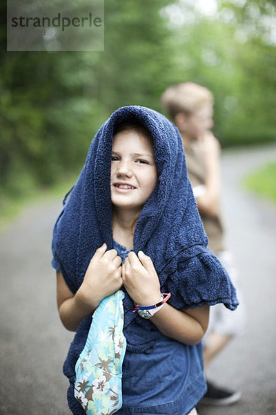 Portrait des Mädchens mit Handtuch auf dem Kopf und Bruder im Hintergrund