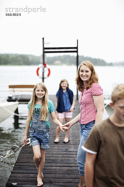 Mutter hält die Hand der Tochter beim Gehen auf dem Pier