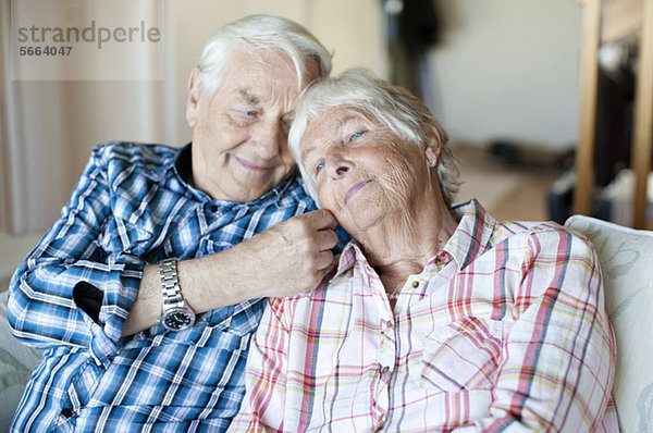 Liebender älterer Mann mit Frau auf dem Sofa im Wohnzimmer