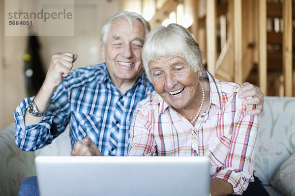 Aufgeregtes Seniorenpaar beim Betrachten des Laptops