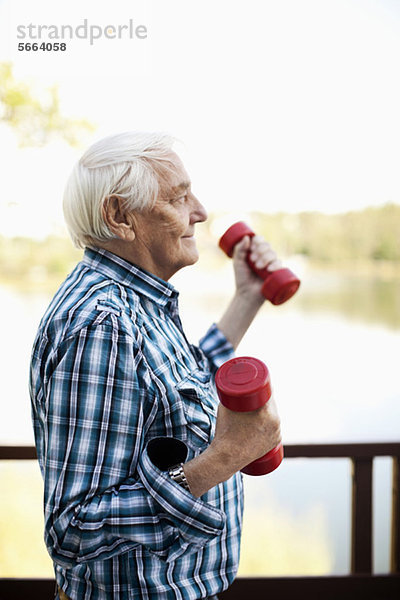 Seitenansicht des älteren erwachsenen Mannes beim Heben des Handgewichts im Freien