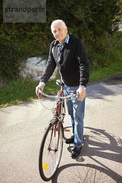 Aktiver Senior mit Fahrrad an einem sonnigen Tag
