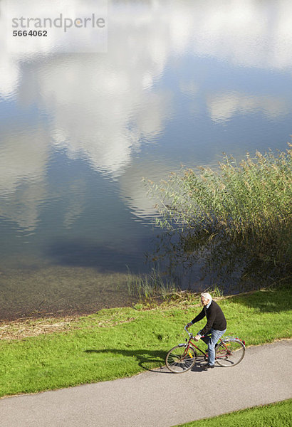 Hochwinkelansicht des Seniorenradfahrers in der Nähe des Sees