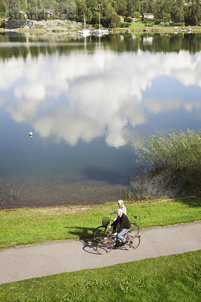 Hochwinkelansicht des Seniorenpaares beim Radfahren am See