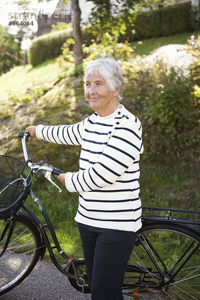 Aktive ältere Frau stehend mit Fahrrad