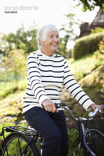 Glückliche Seniorin beim Radfahren im Park