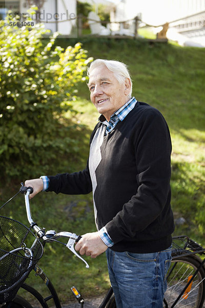 Glücklicher älterer Mann  der mit dem Fahrrad im Park wegguckt.