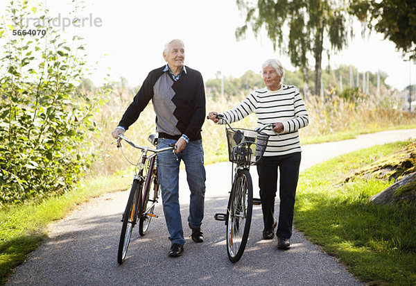 Vorderansicht eines aktiven älteren Paares im Park mit Fahrrädern