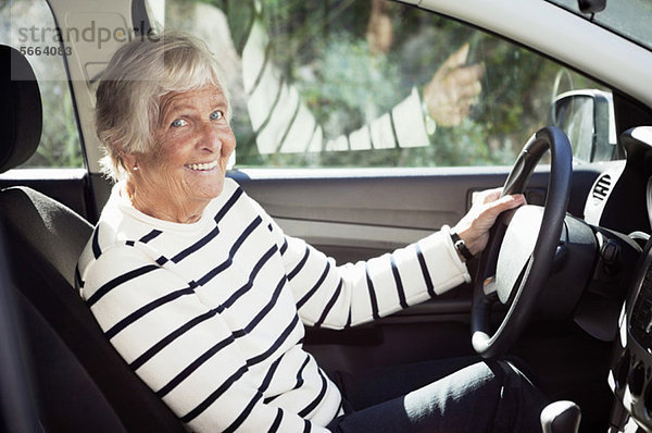 Fröhliche Seniorin auf dem Fahrersitz im Auto sitzend