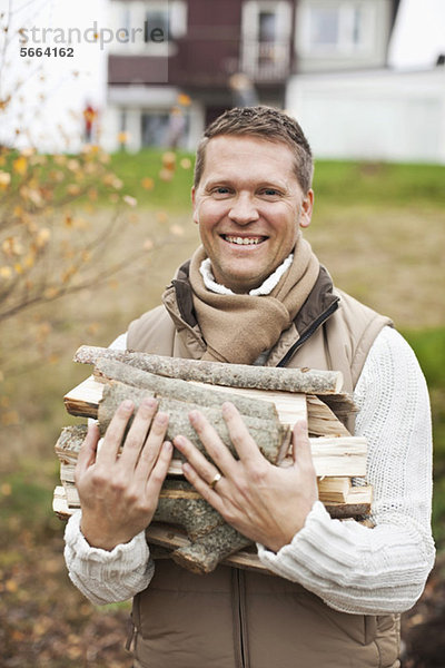 Porträt eines glücklichen Mannes mit Brennholz