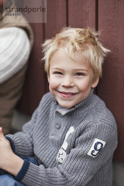 Porträt eines fröhlichen Jungen  der neben dem Vater sitzt.