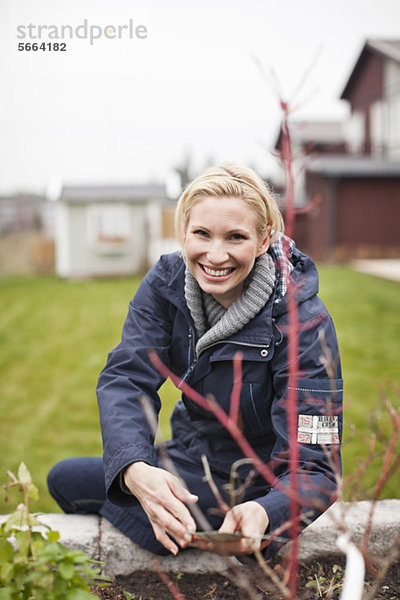 Porträt einer fröhlichen Frau  die im Garten arbeitet.