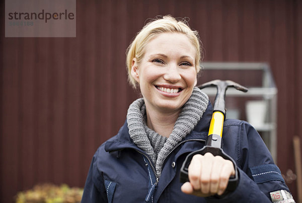 Porträt einer fröhlichen Frau  die eine Schaufel hält.