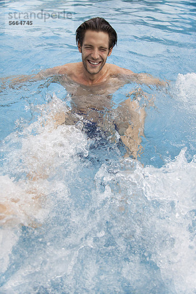 Junger Mann tritt ins Wasser im Schwimmbad