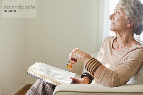 Seniorin liest Buch auf Sofa
