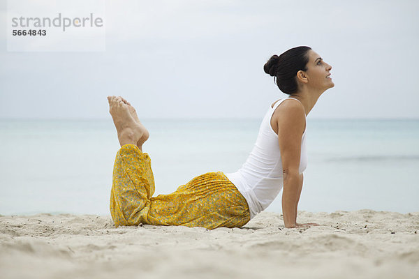 Reife Frau beim Yoga am Strand  Seitenansicht