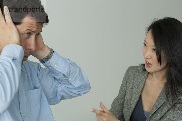 Mann und Frau streiten sich  Mann hält sich die Ohren zu.