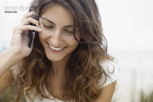 Lächelnde junge Frau spricht am Handy