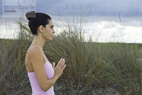 Reife Frau in Gebetsposition im Freien  Seitenansicht