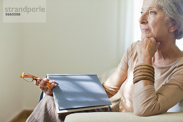 Seniorin sitzend auf Sofa mit Buch