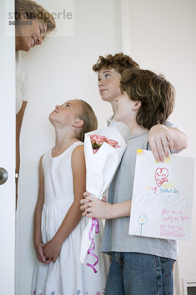 Kinder schenken Mutter Blumen und handgemachte Grußkarte