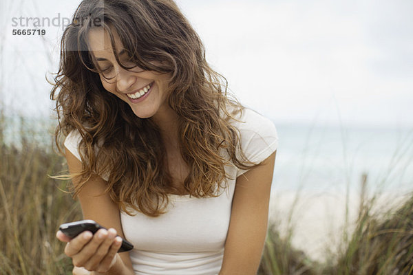 Lächelnde junge Frau beim Anblick des Handys