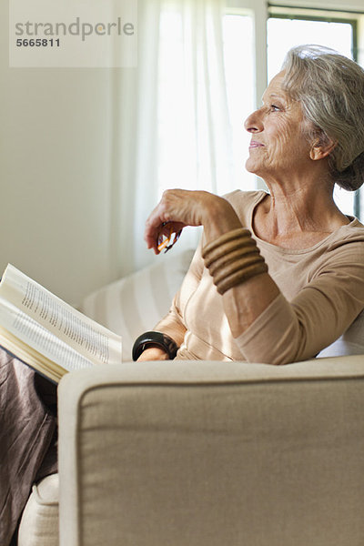 Seniorin liest Buch auf Sofa