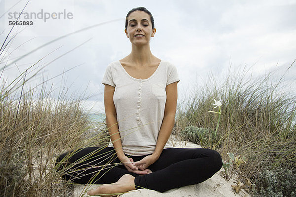Lächelnde reife Frau beim Meditieren am Strand  Portrait