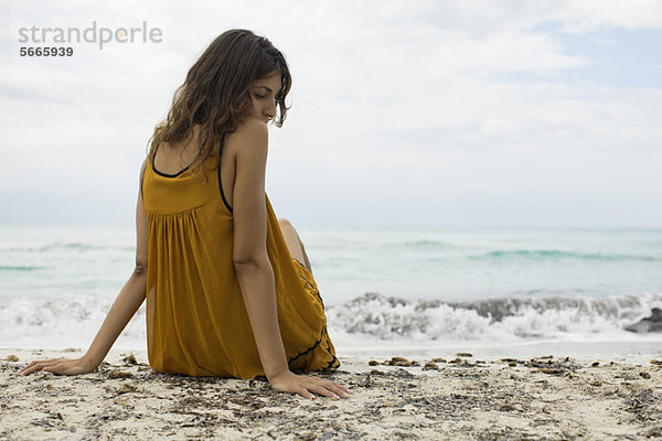 Junge Frau am Strand sitzend