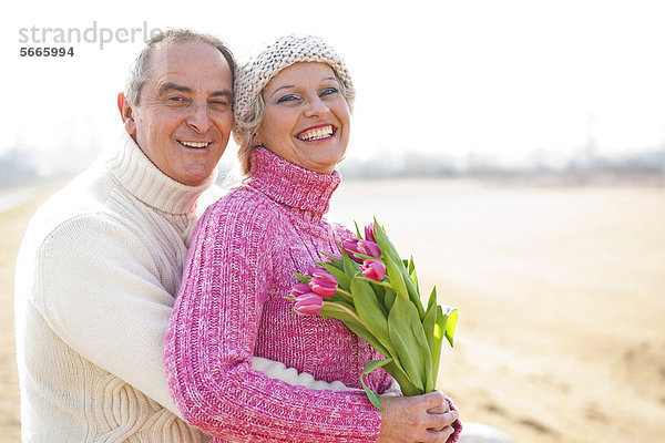 Fröhliches Paar mit Tulpenstrauß im Freien