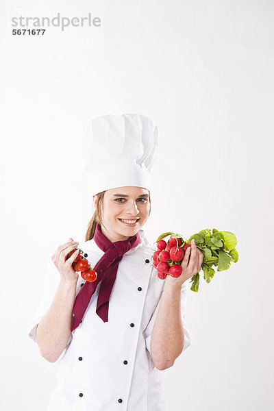 Lächelnde Köchin hält Tomaten und Radieschen