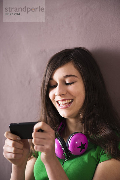 Lachende Teenagerin schaut auf ihr Handy