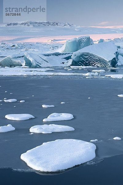 Kleine Eisschollen driften auf dem zufrierenden Gletschersee Jökuls·rlÛn  hinten die Gletscher Brei_amerkurjökull  Breidamerkurjökull und Vatnajökull  Vatnajökull Nationalpark  Island  Europa