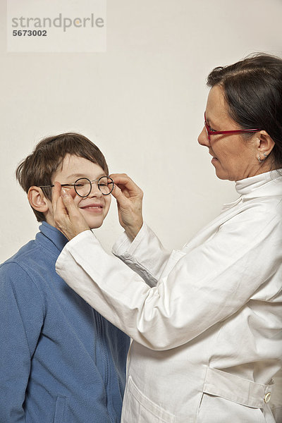 Junge bei Augenärztin  beim Anpassen einer Brille