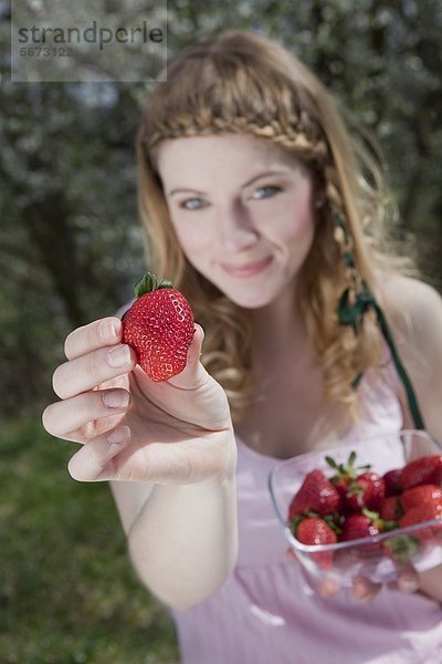 Blonde Frau hält Erdbeeren in der Hand